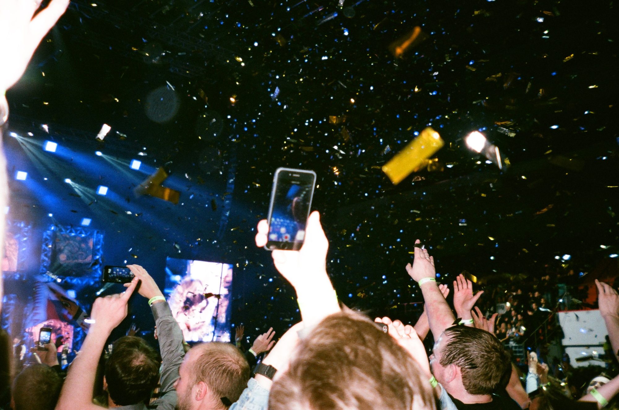 A hand holds a phone up in the middle of the crowd