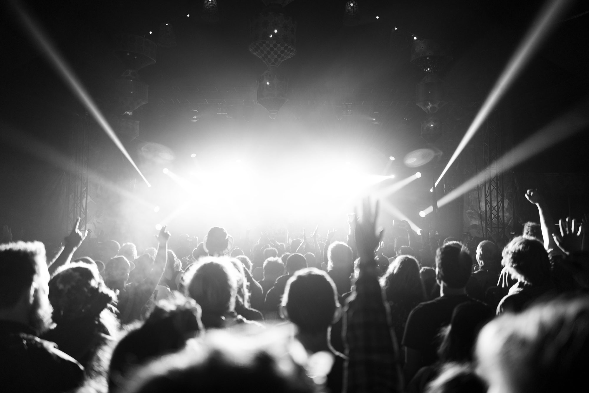 Crowd with hands up in front of a stage with beams of light